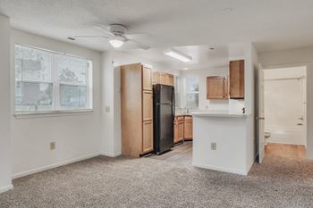 A spacious kitchen with wooden cabinets and a black refrigerator